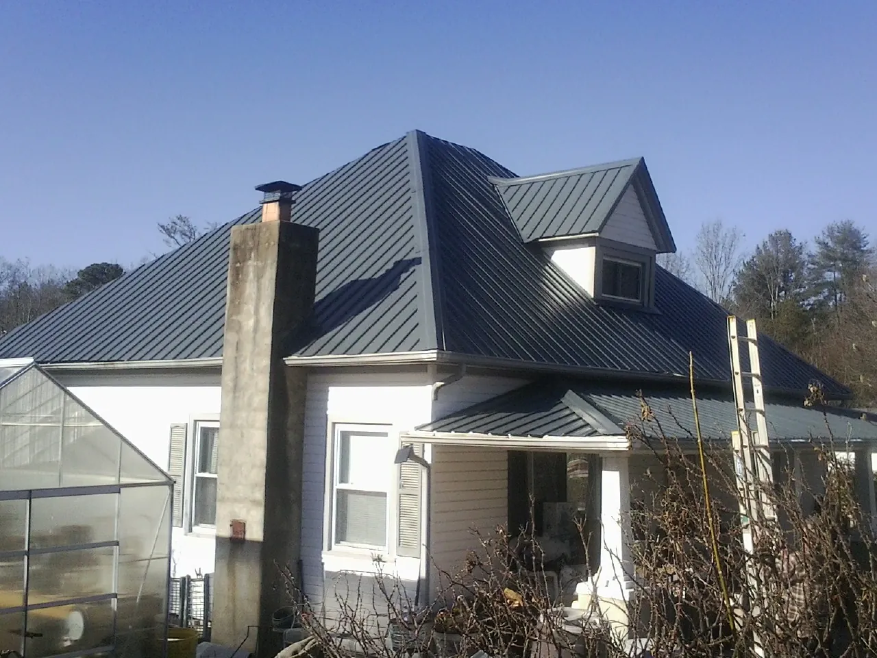 Dark blue standing seam metal roof on a white farmhouse with dormer — Slate & Tile Roof Repair by Roofing Brothers in Chelan