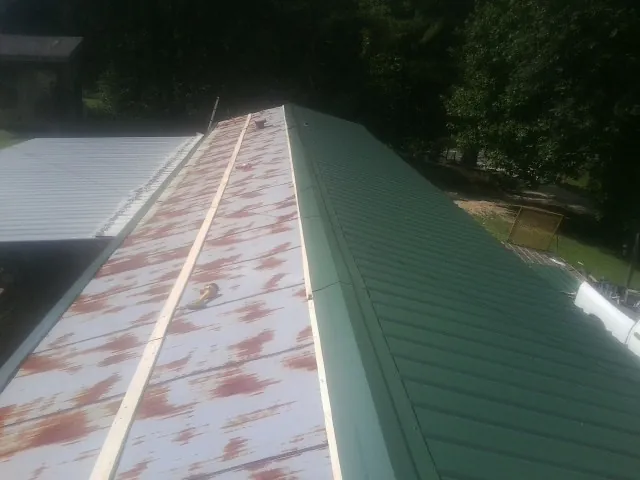 Old rusted panels beside newly installed green metal roofing — Wind Damage Roof Repair by Roofing Brothers in Chelan