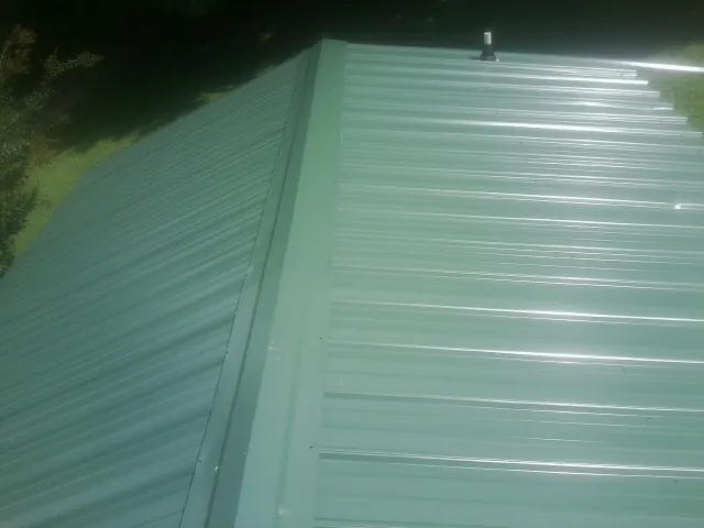 New green metal panels meeting at the ridge of a roof — Flat Roof Repair work by our crew in Chelan