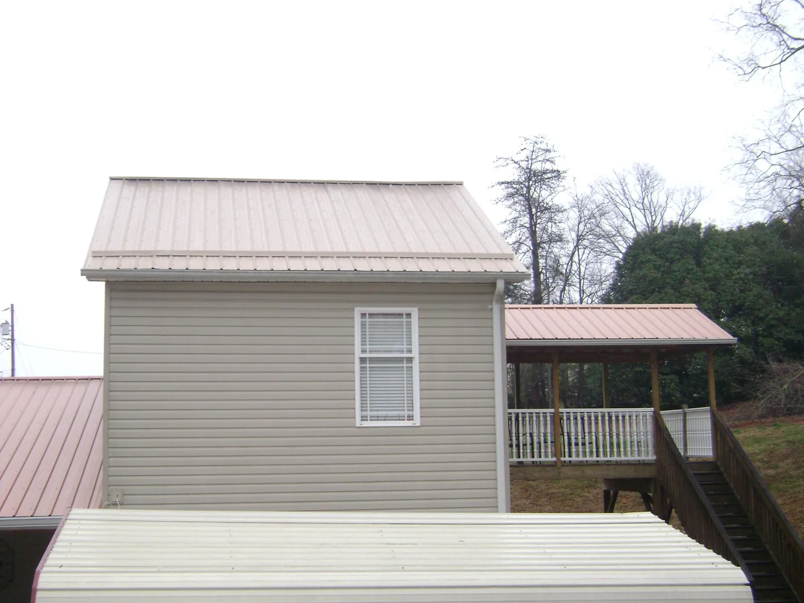 Tan metal roofs on a two story addition and attached porch, from a Roof Replacement job in Chelan