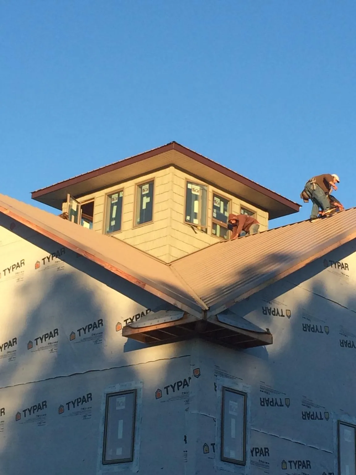 Roofers working around a rooftop cupola on a new metal roof at sunset — Roof Waterproofing in Chelan by Roofing Brothers